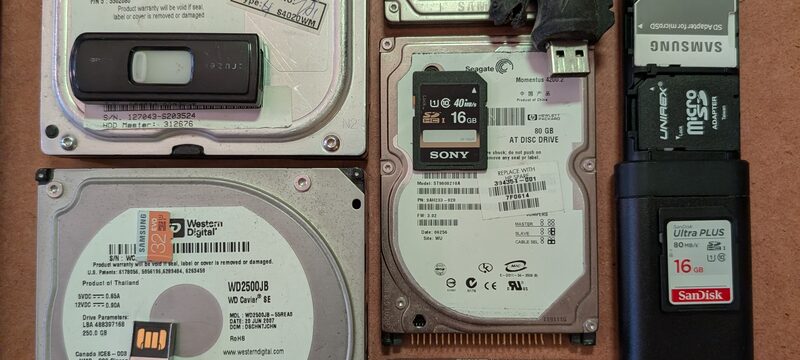 Old hard drives, USB sticks, and CDs ready for migration